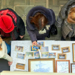 Посетители выставки рассматривают наборы открыток с видами города